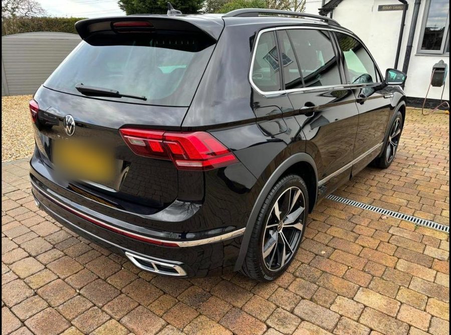 Black Volkswagen Tiguan with a deep gloss finish on a brick-paved drive.