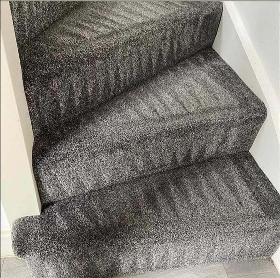 Grey carpet on a staircase, with neat straight lines running through the pile.